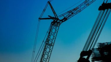 Yapım altında alacakaranlıkta mavi gökyüzünün arkasında hareketli vinçler bir zaman atlamalı