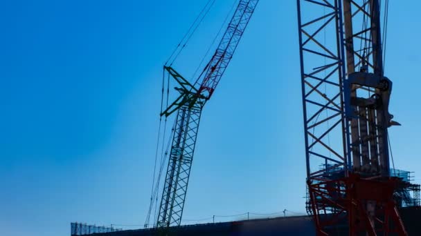 Un lapso de tiempo de grúas móviles detrás del cielo azul en el atardecer en construcción — Vídeo de stock