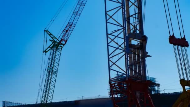 Un lapso de tiempo de grúas móviles detrás del cielo azul en el atardecer en construcción — Vídeos de Stock