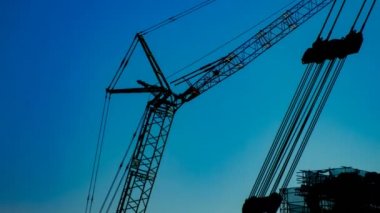Yapım altında alacakaranlıkta mavi gökyüzünün arkasında hareketli vinçler bir zaman atlamalı