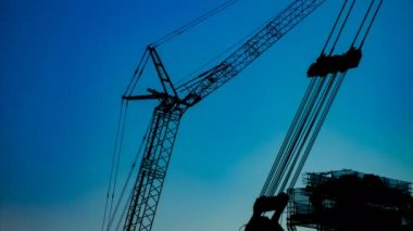 Yapım altında alacakaranlıkta mavi gökyüzünün arkasında hareketli vinçler bir zaman atlamalı
