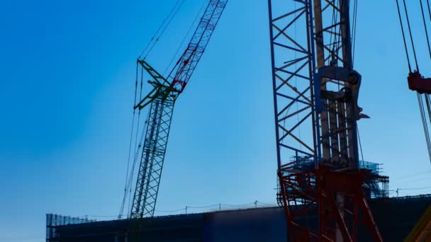 A time lapse of moving cranes behind the blue sky at the under construction dusk — Stock Video