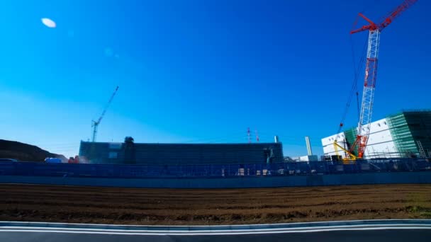 Un time lapse di gru in movimento dietro il cielo blu al colpo largo in costruzione — Video Stock