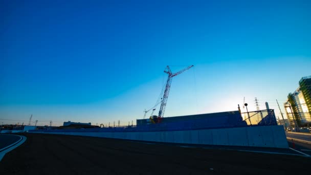 Um lapso de tempo de guindastes em movimento atrás do céu azul no tiro de largura sob construção — Vídeo de Stock