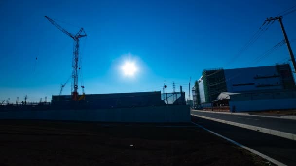 Un laps de temps de grues mobiles derrière le ciel bleu au large plan en construction — Video