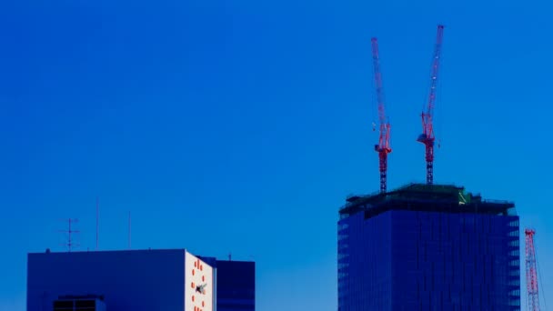 Een tijdsverloop van bewegende kranen op de top van het gebouw achter de blauwe lucht in Tokio — Stockvideo