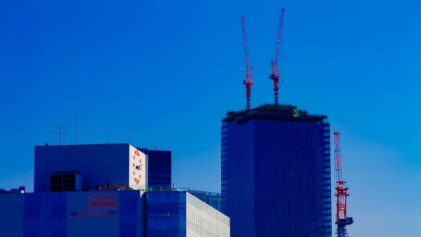 Een tijdsverloop van bewegende kranen op de top van het gebouw achter de blauwe lucht in Tokio — Stockvideo