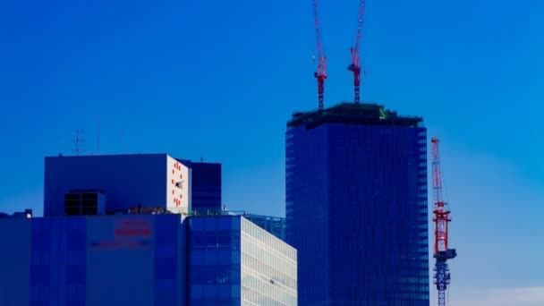 Un lapso de tiempo de grúas en movimiento en la parte superior del edificio detrás del cielo azul en Tokio — Vídeo de stock