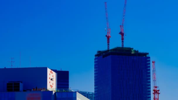 En tidsfördröjning av rörliga kranar på toppen av byggnaden bakom den blå himlen i Tokyo — Stockvideo