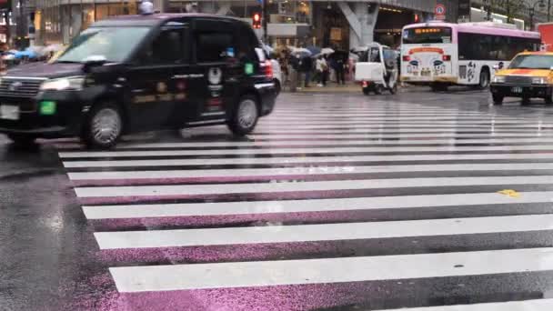 Mozgó autók és a gyaloglás az emberek Shibuya átkelés Tokió esős napon — Stock videók
