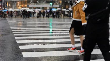 Tokyo yağmurlu bir günde Shibuya geçişinde yürüyüş insanlar