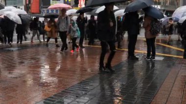 Tokyo yağmurlu bir günde Shibuya geçişinde yürüyüş insanlar