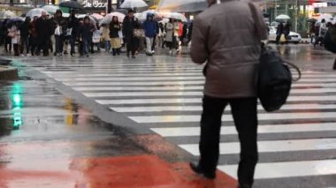 Tokyo yağmurlu bir günde Shibuya geçişinde yürüyüş insanlar