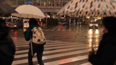 Tokyo yağmurlu bir günde Shibuya geçişinde yürüyüş insanlar