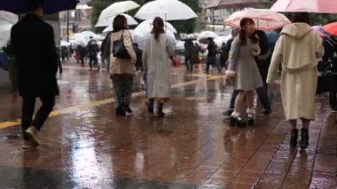 Tokyo yağmurlu bir günde Shibuya geçişinde yürüyüş insanlar