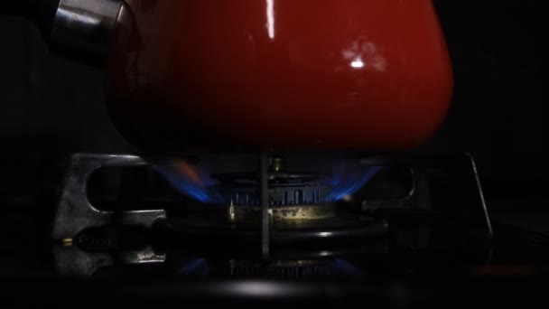 Allumage de la chaleur sous la casserole rouge dans la cuisine 