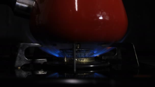 Allumage de la chaleur sous la casserole rouge dans la cuisine 