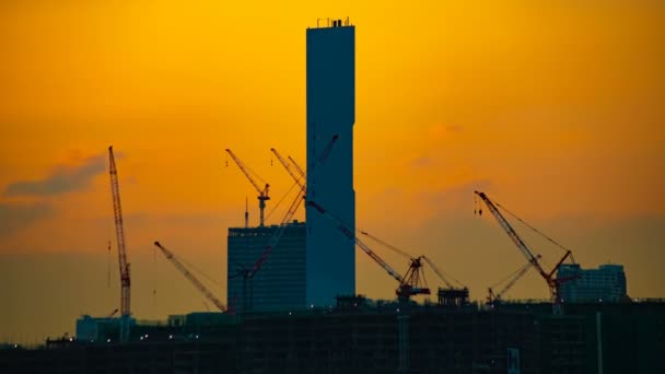 Un lapso de tiempo de grúas en movimiento en la construcción en Tokio al atardecer zoom — Vídeos de Stock