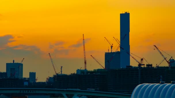 Un lapso de tiempo de grúas en movimiento en la construcción en Tokio al atardecer panorámica de tiro ancho — Vídeos de Stock