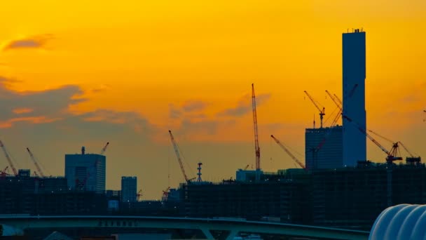 Un lapso de tiempo de grúas en movimiento en la construcción en Tokio al atardecer panorámica de tiro ancho — Vídeos de Stock