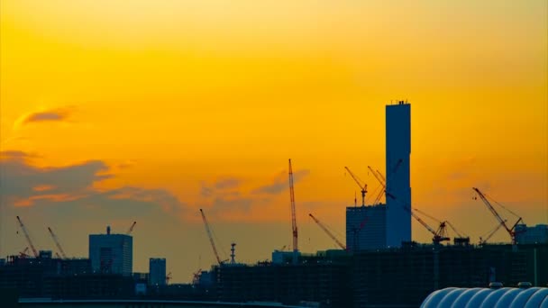 Un lapso de tiempo de grúas en movimiento en la construcción en Tokio al atardecer inclinación de tiro ancho — Vídeos de Stock