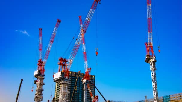 Um lapso de tempo de guindastes em movimento na construção em Tóquio tiro largo panning — Vídeo de Stock