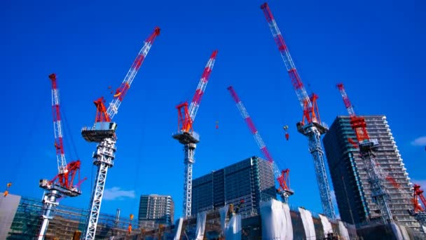 Um lapso de tempo de guindastes em movimento na construção em Tóquio ampla inclinação tiro — Vídeo de Stock