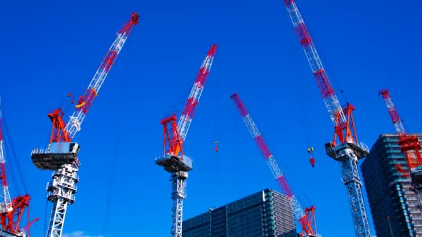 Un lapso de tiempo de grúas en movimiento en la construcción en Tokio zoom de tiro ancho — Vídeo de stock