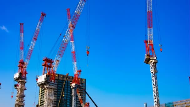 Um lapso de tempo de guindastes em movimento na construção em Tóquio zoom tiro largo — Vídeo de Stock