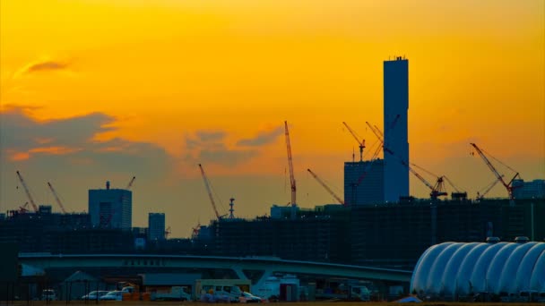 Un lapso de tiempo de grúas en movimiento en la construcción en Tokio al atardecer — Vídeos de Stock