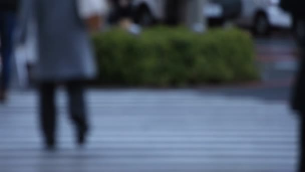 Parties du corps des personnes qui marchent au croisement à Shinjuku Tokyo jour de pluie — Video