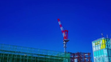 Tokyo 'da inşaat altında mavi gökyüzü arkasında Hareketli vinçler bir zaman atlamalı