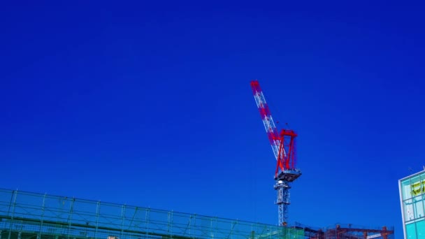 Un lapso de tiempo de grúas en movimiento detrás del cielo azul en la construcción en Tokio — Vídeos de Stock