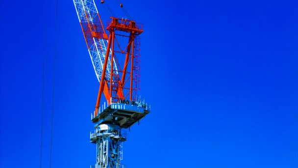 Um lapso de tempo de guindastes em movimento atrás do céu azul na construção em construção em Tóquio — Vídeo de Stock