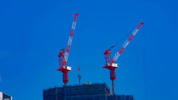 Un timelapse de grúas en construcción detrás del cielo azul en Tokio — Vídeos de Stock