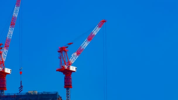 Un timelapse de grúas en construcción detrás del cielo azul en Tokio — Vídeos de Stock