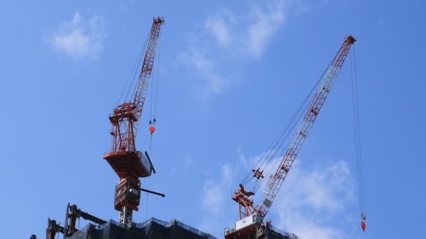 Перемещение кранов в строящемся здании за голубым небом в Токио — стоковое видео