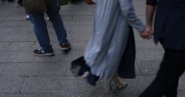 Asakusa'da taş döşeli yolda yürüyen insanların vücut parçaları