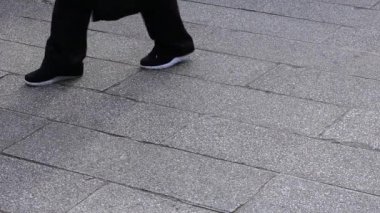Asakusa'da taş döşeli yolda yürüyen insanların vücut parçaları