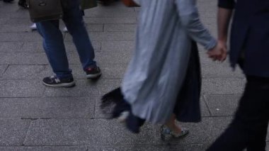 Asakusa'da taş döşeli yolda yürüyen insanların vücut parçaları