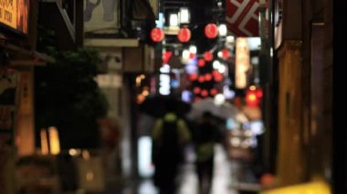 Nakano Tokyo 'nun neon sokağında yürüyen insanlar. Yağmurlu bir gün.