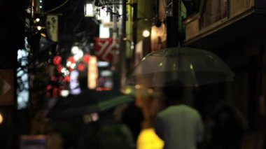Nakano Tokyo 'nun neon sokağında yürüyen insanlar. Yağmurlu bir gün.