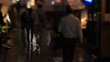 Nakano Tokyo 'nun neon sokağında yürüyen insanlar. Yağmurlu bir gün.