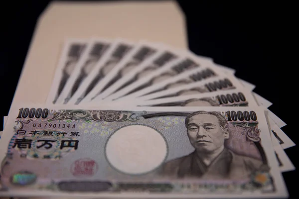 Moeda japonesa 100.000 ienes com envelope no fundo preto close-up — Fotografia de Stock
