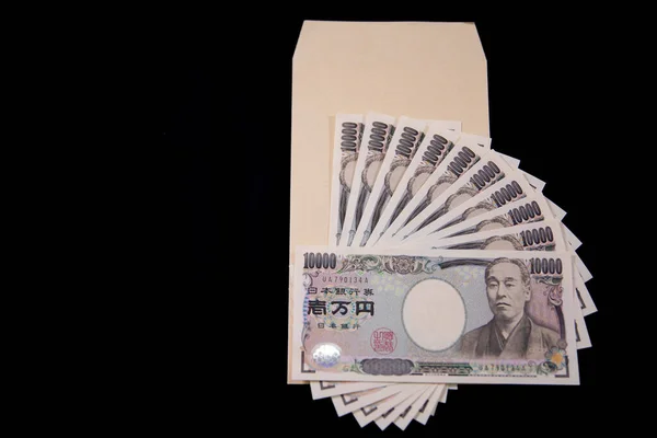 Moeda japonesa 100.000 ienes com envelope no espaço de cópia de fundo preto — Fotografia de Stock