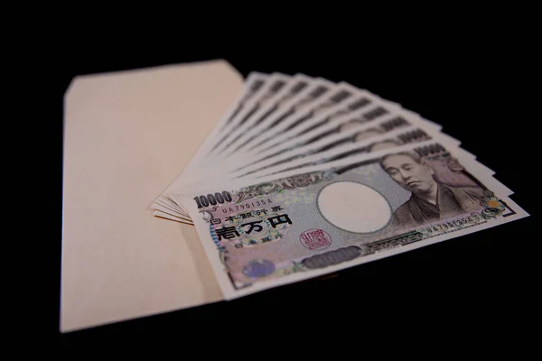 Moeda japonesa 100.000 ienes com envelope no fundo preto — Fotografia de Stock