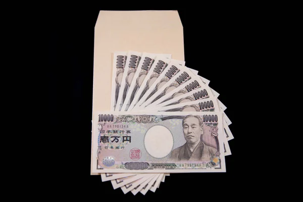 Moeda japonesa 100.000 ienes com envelope no fundo preto — Fotografia de Stock