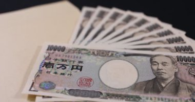Japon para birimi 100,000 yen ve siyah arkaplanda zarf var.