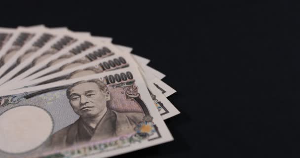 Japońska waluta 100.000 jenów z kopertą na czarnym tle panning — Wideo stockowe