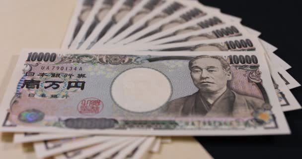 Moneda japonesa 100.000 yenes con el sobre en la inclinación de fondo negro enfoque — Vídeos de Stock